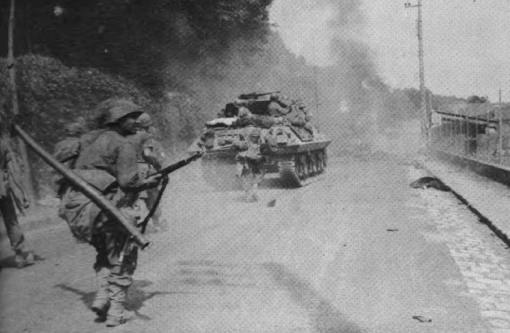 Picture of tank and soldiers moving through Europe along a road